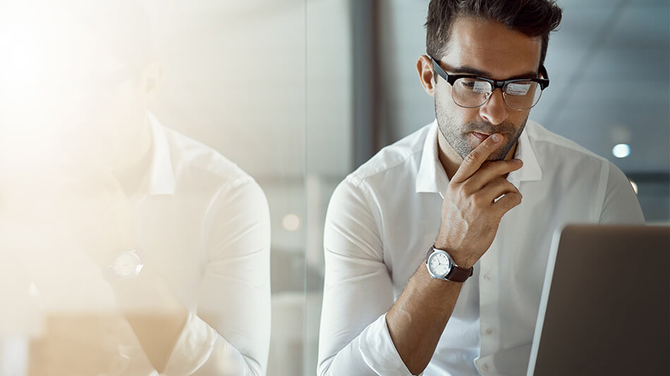 A middle age man with glasses looking at his laptop thinking.